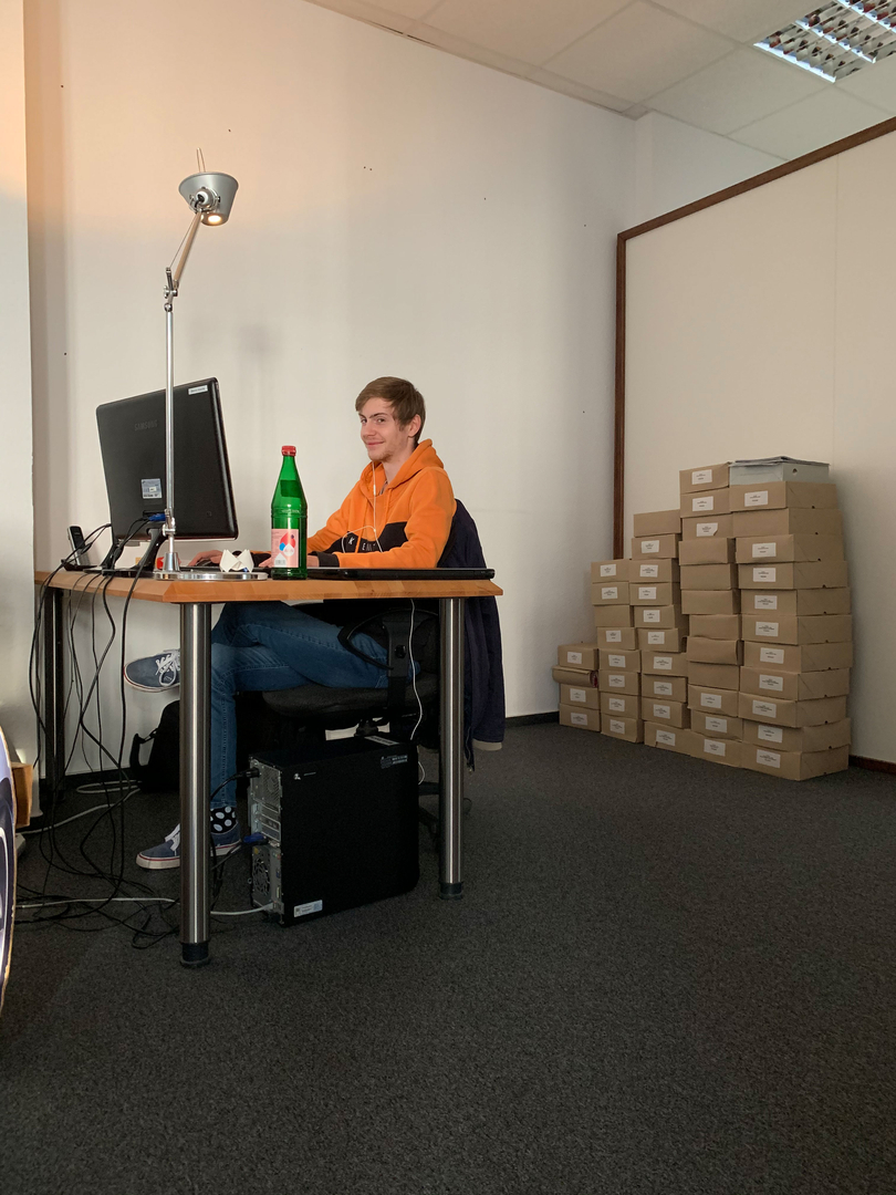 Marvin am Schreibtisch mit gepackten Kartons im Hintergrund