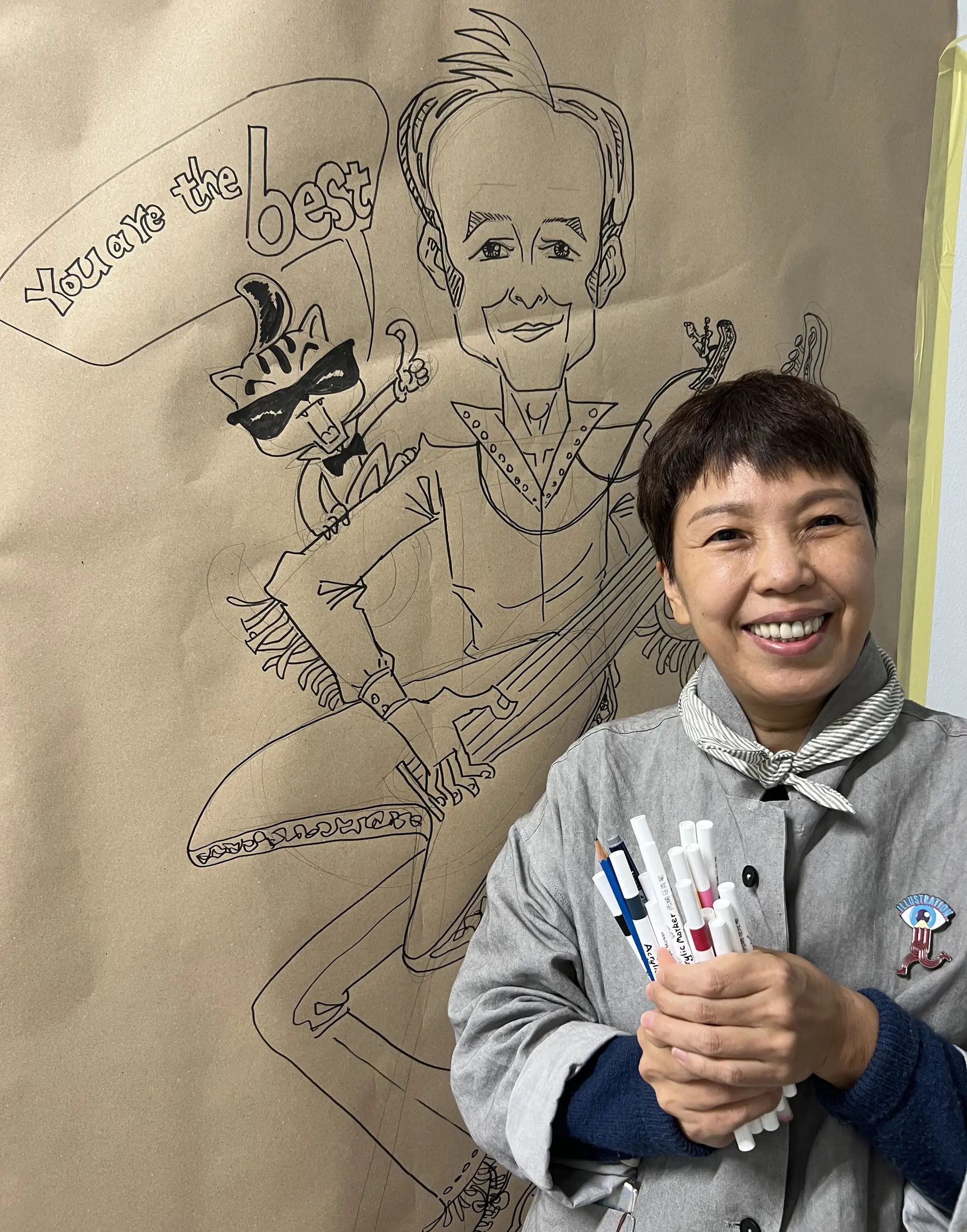 Foto der Künstlerin Xu Jingru hinter einer Zeichnung, mit Filzstiften in den Händen.