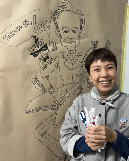 Foto der Künstlerin Xu Jingru hinter einer Zeichnung, mit Filzstiften in den Händen.