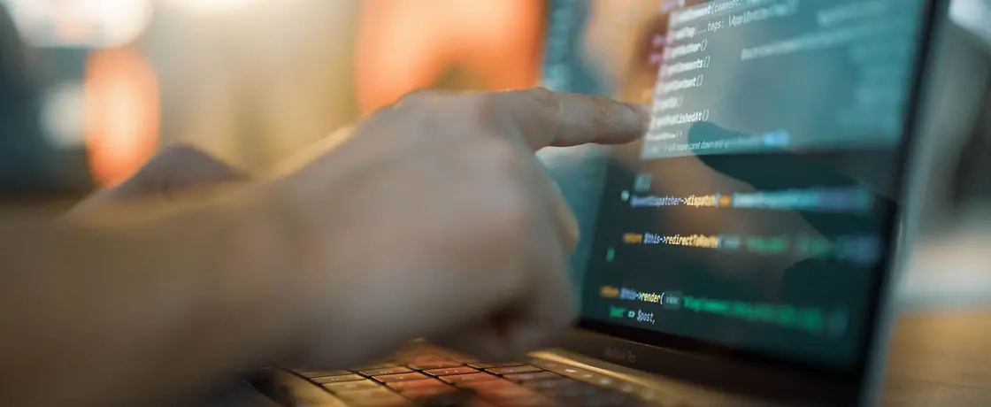 Foto eines Zeigefingers, der auf Code auf einem Computerbildschirm zeigt