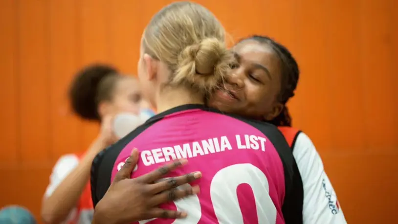 Zwei Handballspielerinnen des SC Germania List feiern einen Erfolg mit einer Umarmung