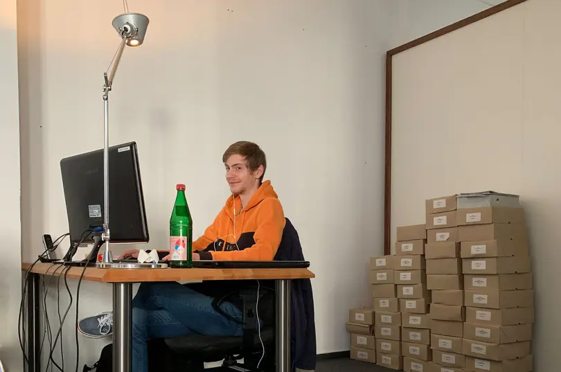 Marvin am Schreibtisch mit gepackten Kartons im Hintergrund