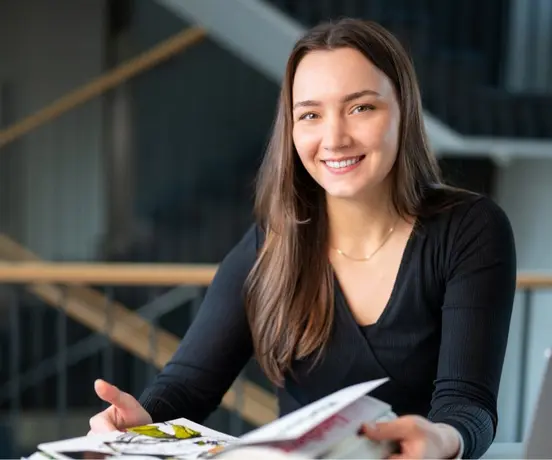 Foto einer Person aus dem Grafikteam, die lächelnd ein Grafikbuch durchblättert